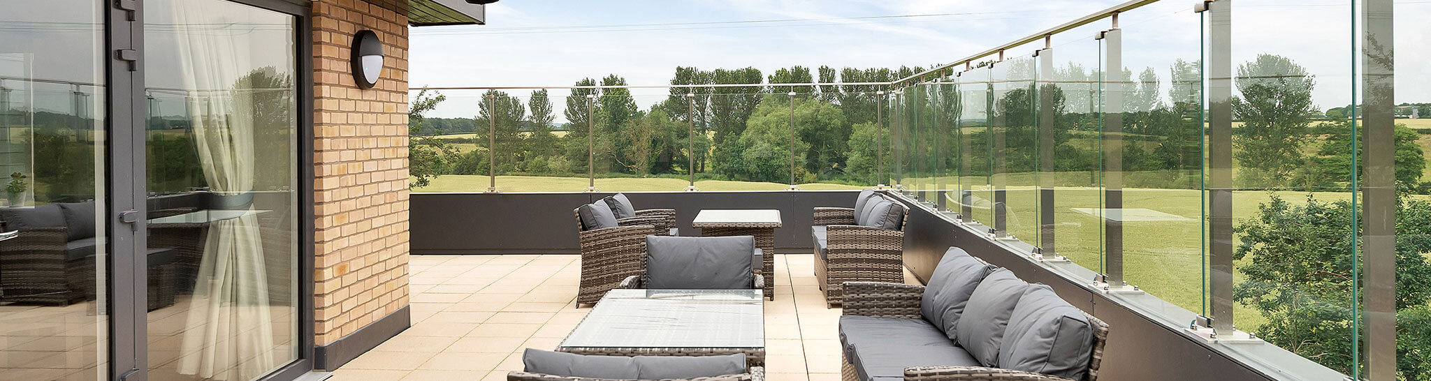 Spacious balcony with modern outdoor, ratten garden  furniture overlooking a green landscape