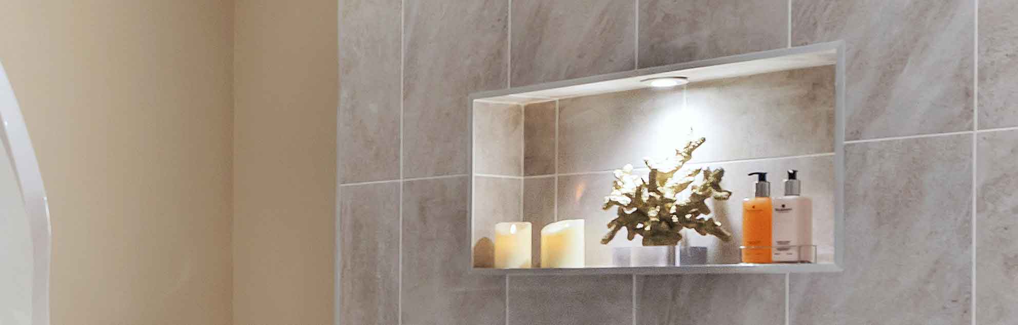 Modern décorated bathroom shelf with decorative items including lit candles, a small plant, and toiletry bottles